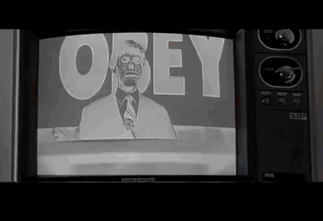 Gif du film « They live ». Une première scène avec l’acteur principal en couleur et ses lunettes qui regarde la télévision avec le présentateur et derrière ce-dernier "Obey".